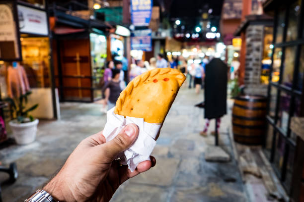 meat pastry in market, hand held meat pastry in market, hand held, people blurred in background argentina food stock pictures, royalty-free photos & images