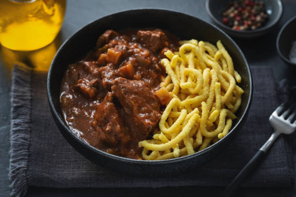 Meat ragout with noodles served in bowl on dark background. stock photo