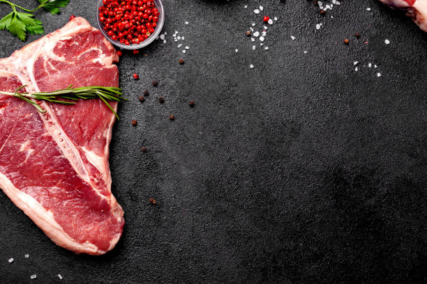 Meat raw steaks lie on a black background with vegetables, tomatoes, marasmade, mushrooms. background image. side view, copy space, top view stock photo
