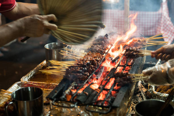 Meat skewers cook over hot coals in Singapore's Satay Street food market stock photo