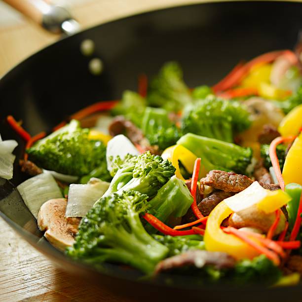meat vegetables in a frying pan stock photo