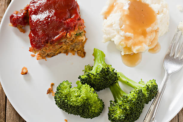 Meatloaf Dinner "An overhead closeup shot of a white plate with a portion of meat loaf covered with tomato sauce, mashed potatoes with brown gravy and several lightly steamed spears of green broccoli." meatloaf stock pictures, royalty-free photos & images