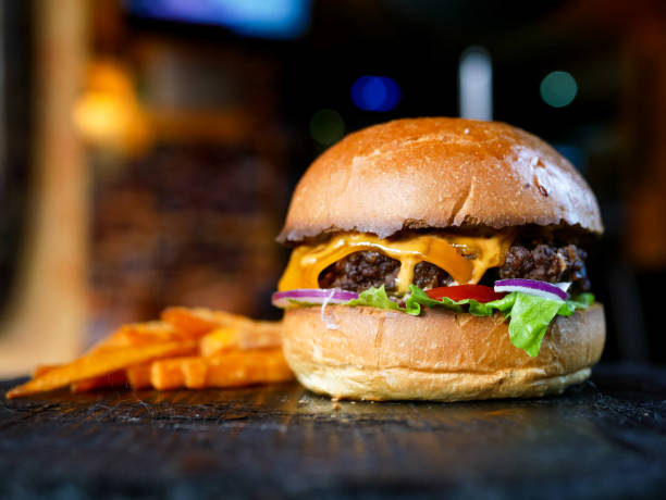 Meaty hamburger and fries on a table Meaty hamburger and fries on a table hamburger stock pictures, royalty-free photos & images