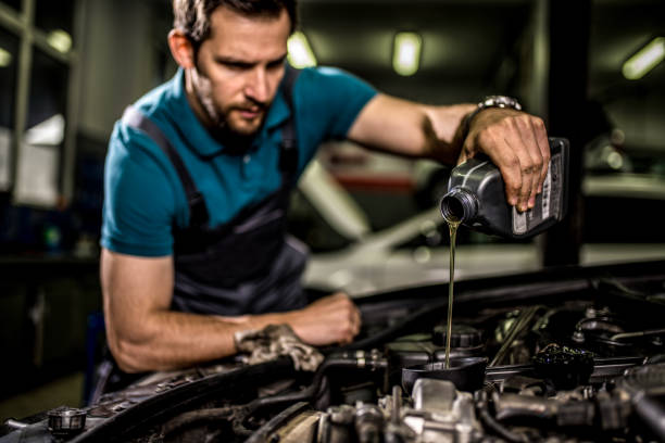 Mechanic changing oil on the vehicle at car workshop. stock photo
