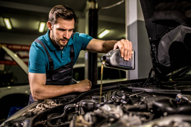 Mechanic changing oil on the vehicle at car workshop. stock photo