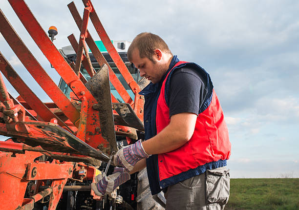 Mechanic fixing plow on the tractor Young mechanic fixing plow on the tractor agricultural equipment stock pictures, royalty-free photos & images
