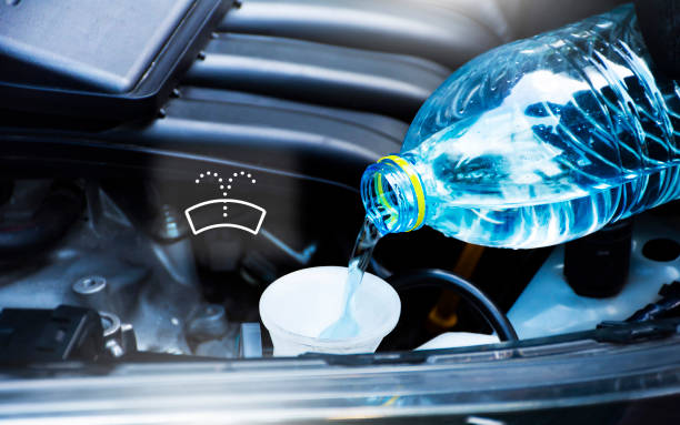Mechanic hand is filling clean water into windshield washer water tank with windshield washer icon stock photo