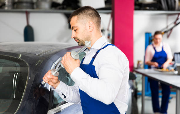 Mechanic performing dent repair Professional mechanic performing dent repair on car body before painting in auto workshop dented stock pictures, royalty-free photos & images