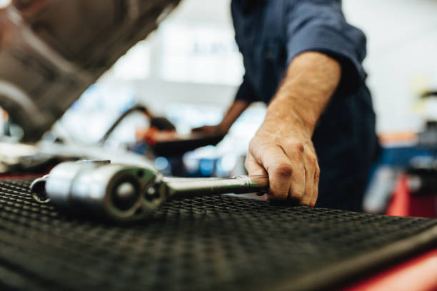 Mechanic picking up a ratchet spanner Hand of mechanic picking up a ratchet spanner from table in auto workshop. Mechanic working on garage with tools. selective focus stock pictures, royalty-free photos & images