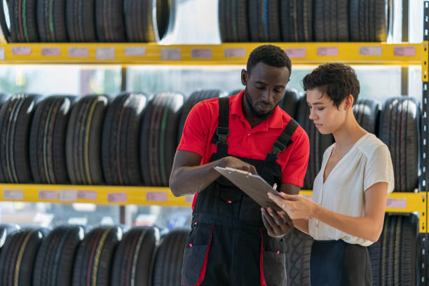 A mechanic talking to female customer The Auto mechanic talking to female customer in tires shop, car auto service, garage tire vehicle part stock pictures, royalty-free photos & images
