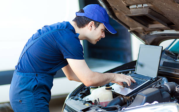Mechanic using a laptop computer to check the car engine stock photo