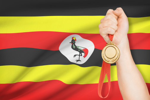Sportsman holding gold medal with flag on background - Republic of Uganda