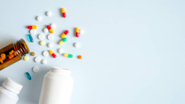 パステルブルーの背景にこぼれる医療ボトルや薬の丸薬。コピースペースのあるトップビュー。ヘルスケア、薬局、医学の概念 - 薬 ストックフォトと画像