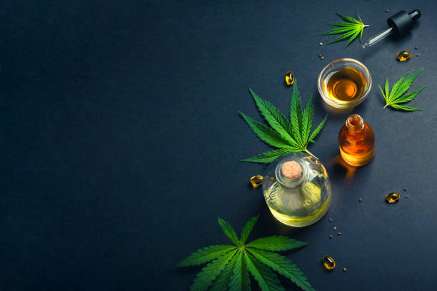 Medical CBD oil, tincture on black trendy background with cannabis leaves stock photo