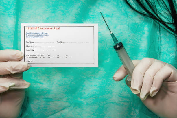 Medical concept of female with a syringe and white gloves displaying document for coronavirus protection immunization shot. stock photo
