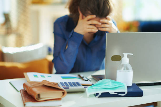medical mask and hand disinfectant and stressed woman Closeup on medical mask and hand disinfectant and stressed woman in background in temporary home office during the coronavirus epidemic in the house in sunny day. frustration stock pictures, royalty-free photos & images