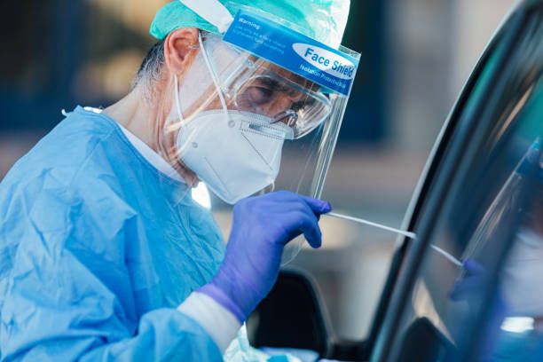 ppe giyen sağlık personeli, ellerinde bir bez ile pcr gerçekleştiren, o covid-19 ile enfekte olup olmadığını tespit etmek için arabasının içinde bir hasta üzerinde - tıbbi test stok fotoğraflar ve resimler