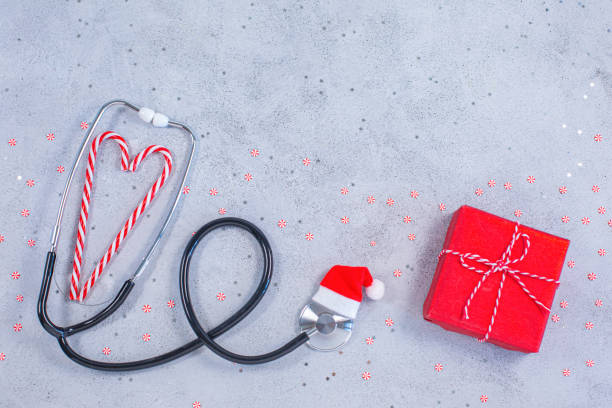 Medical stethoscope in a red Santa Claus hat with gift box and candies stock photo