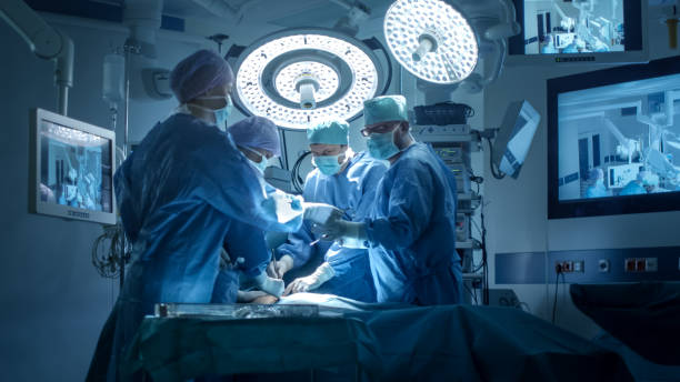 medizinisches team bei chirurgischer operation im modernen operationssaal - chirurg stock-fotos und bilder