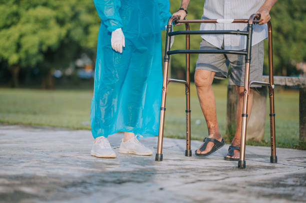 Medicare Asian Chinese female physical therapist correcting posture helping senior man walking in public park with mobility walker Medicare Asian Chinese female physical therapist correcting posture helping senior man walking in public park with mobility walker diabetic foot stock pictures, royalty-free photos & images