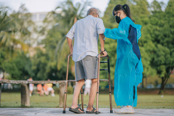 medicare asian chinese female physical therapist correcting posture helping senior man walking in public park with mobility walker medicare asian chinese female physical therapist correcting posture helping senior man walking in public park with mobility walker diabetic foot stock pictures, royalty-free photos & images