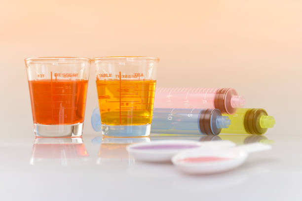 Medicinal cup, oral syringe and teaspoon filled with oral syrup medicine. stock photo