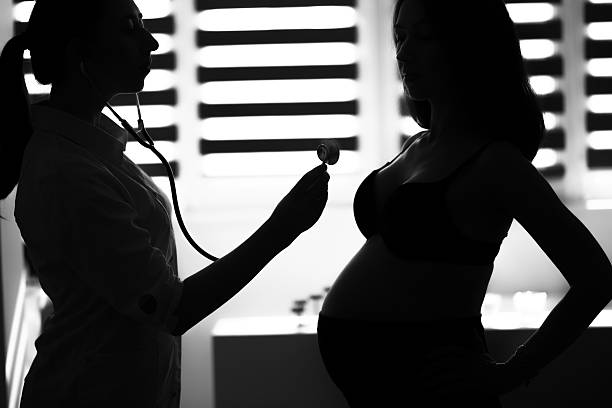 Medicine pregnant Silhouette female medicine doctor holding stethoscope to pregnant woman standing for encouragement, empathy, cheering, support, medical examination. New life of abortion concept. B / W style abortion clinic stock pictures, royalty-free photos & images