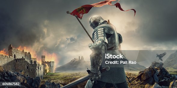 istock Medieval Knight With Banner and Sword Standing Near Burning Castle 604867582