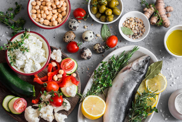 Mediterranean style food background. Fish, vegetables, herbs, chickpeas, olives, cheese on grey background, top view. Healthy food concept. Flat lay stock photo