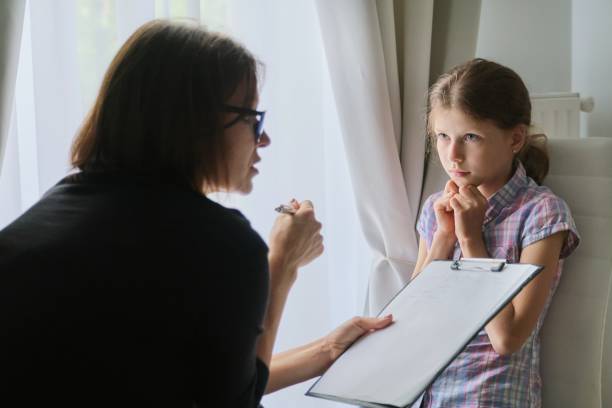 Meeting child girl with school counselor psychotherapist. Meeting child girl with school counselor therapist. Children mental health, psychological assistance, counselor takes notes on clipboard school counselor stock pictures, royalty-free photos & images