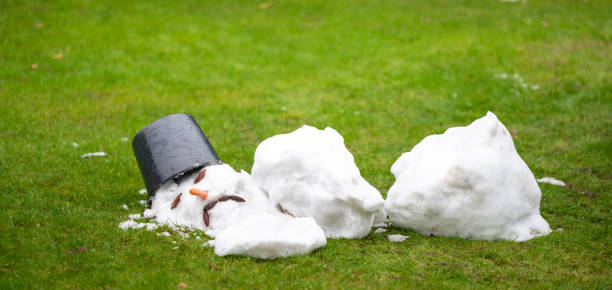 A melted snow man with a sad face as symbol of the end of the winter. stock photo