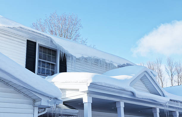 Melting Snow And Icicles On Residential House Roof Edge stock photo