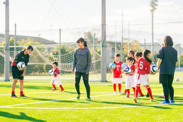 Members of female kids' soccer or football team listening to their coach's instructors before stating training stock photo
