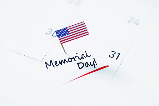 US Memorial Day note over white calendar pinned by a tiny American flag to remind its importance.  US Memorial Day reminder concept. Horizontal composition with copy space.