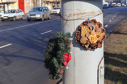 Memorial wreaths on a pole next to the road near a scene of a traffic accident