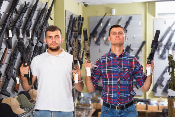 Men 20-30 years old are choosing pneumatic rifle Men 20-30 years old are choosing pneumatic rifle in airsoft store. militia stock pictures, royalty-free photos & images