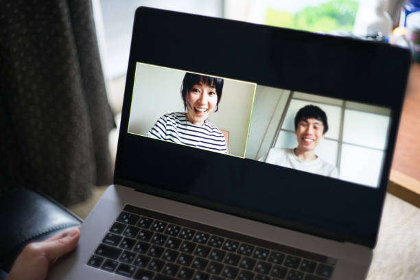 Men and women sitting on the sofa at home and having a fun video call using a laptop stock photo