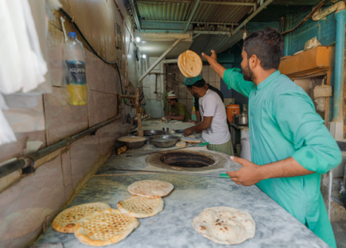 Lahore, Pakistan  - October 31, 2021: Men baking naan in Lahore, Pakistan