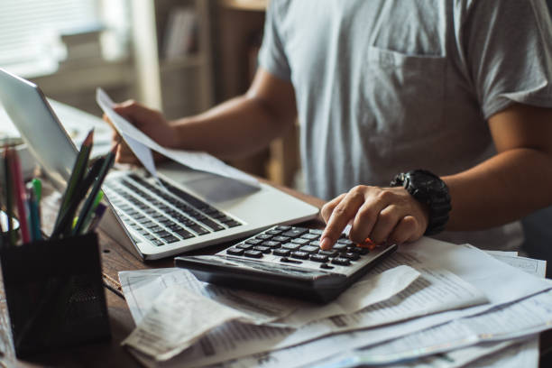 hombres es calcular el costo de la factura. ella está presionando la calculadora. - electronic invoice fotografías e imágenes de stock