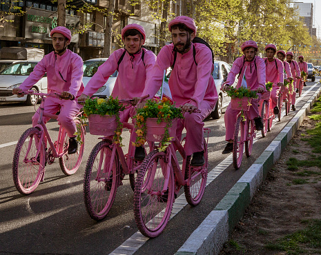 Tehran, Iran - 2019-04-03 - Men ride bicycles in pink to promote new bike rental company.