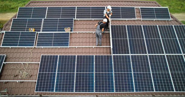 Men technicians mounting photovoltaic solar moduls on roof of house. stock photo