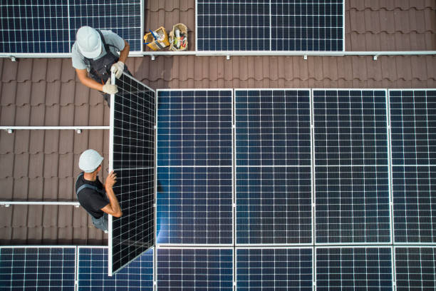 Men technicians mounting photovoltaic solar moduls on roof of house. stock photo