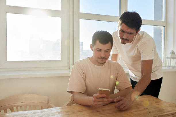 Men using smartphone at home together stock photo
