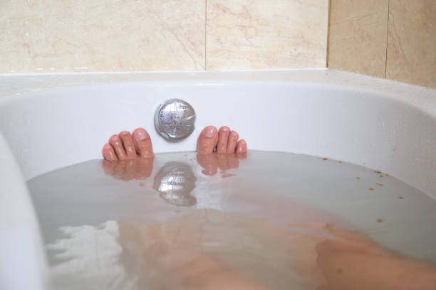Men's feet in a relaxing aromatic salt bath in an hotel bathtub. stock photo