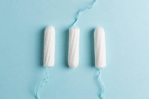 menstruele tampon op een blauwe achtergrond. menstruatie tijd. hygiëne en bescherming - tampons stockfoto's en -beelden