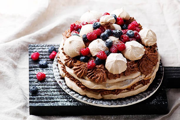 meringue cake with chocolate mousse and berries meringue cake with chocolate mousse and berries pavlova dessert photos stock pictures, royalty-free photos & images