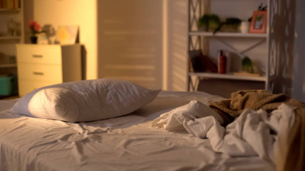 Cama desordenada, almohada blanca con manta tirada en la cama sin hacer, concepto de dormir demasiado - foto de stock