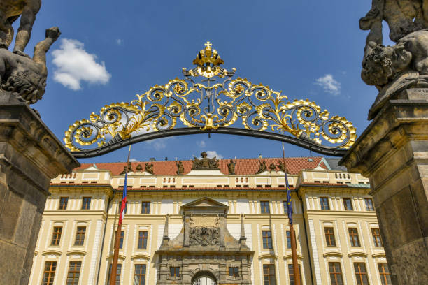 Metal arch over the gates at the entrance to Prague Castle Prague, Czech Republic - August 2018: Main entrance to Prague Castle. The Castle is a landmark in the city and a popular tourist attraction. hradcany castle stock pictures, royalty-free photos & images