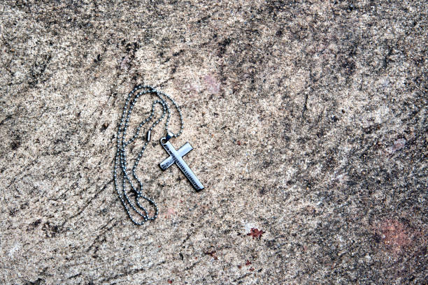 Metal Christian cross necklace on stone background stock photo