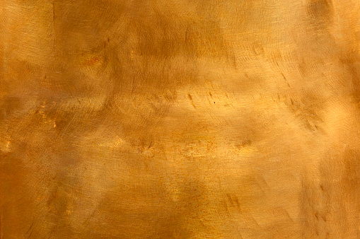 Brushed brown-golden copper or bronze surface, with visible brush strokes. The sheet metal has an appealing cloudy, wavy texture. Horizontal orientation. The image has been shot outdoors during natural day light, full frame and close up. Ideal for backgrounds. The dimensions of the photo are 4223 x 2805 px